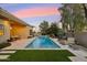 Backyard with a rectangular pool, fire pit, outdoor grill and desert landscaping at dusk at 2625 N 24Th St # 36, Mesa, AZ 85213