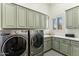 Laundry room features gray washer and dryer, green cabinets, white countertops and geometric tile floor at 2625 N 24Th St # 36, Mesa, AZ 85213