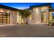 Modern home with a grand entrance featuring a stone facade, large windows, tree, and ample driveway space at 28110 N 96Th Pl, Scottsdale, AZ 85262