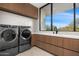 Laundry room with modern appliances, wood cabinets, sink, and scenic window view at 28110 N 96Th Pl, Scottsdale, AZ 85262