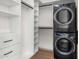 A well-organized laundry room with modern, stacked washer and dryer units and ample white shelving for storage at 28110 N 96Th Pl, Scottsdale, AZ 85262