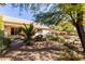 Backyard featuring desert landscaping, mature trees and shrubs, rock ground cover, and a covered patio at 5373 W Dublin Ct, Chandler, AZ 85226