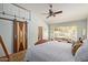 Bedroom featuring a unique barn door, hardwood flooring, ceiling fan, and natural light at 5373 W Dublin Ct, Chandler, AZ 85226