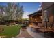 Stunning backyard with a covered patio, outdoor lighting, lush lawn, and desert landscaping at sunset at 9290 E Thompson Peak Pkwy # 444, Scottsdale, AZ 85255