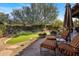 Landscaped backyard with a lush lawn, desert plants, stone pathway and comfortable outdoor seating under an umbrella at 9290 E Thompson Peak Pkwy # 444, Scottsdale, AZ 85255