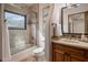 Bathroom showcasing a glass shower/tub combo, wood vanity, and neutral tile accents at 9290 E Thompson Peak Pkwy # 444, Scottsdale, AZ 85255