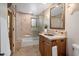 Cozy bathroom with a glass-enclosed shower/tub, warm-toned tiles, and a wood vanity for storage at 9290 E Thompson Peak Pkwy # 444, Scottsdale, AZ 85255