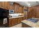 Beautiful kitchen featuring wooden cabinetry, stainless steel appliances, and granite countertops with a stone tile floor at 9290 E Thompson Peak Pkwy # 444, Scottsdale, AZ 85255