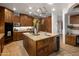 Kitchen island featuring granite countertops, wood cabinetry, a sink, cooktop and a decorative pot rack overhead at 9290 E Thompson Peak Pkwy # 444, Scottsdale, AZ 85255