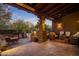 Covered patio with cozy seating and outdoor grilling area overlooking a landscaped backyard at twilight at 9290 E Thompson Peak Pkwy # 444, Scottsdale, AZ 85255