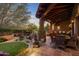 Covered patio with outdoor dining and seating areas overlooking a manicured yard with mature trees at dusk at 9290 E Thompson Peak Pkwy # 444, Scottsdale, AZ 85255