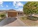 Brick ranch house with a large tree, well-maintained lawn, and a wooden garage door at 9890 N Balboa Dr, Sun City, AZ 85351