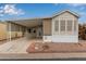 Tan mobile home with covered carport and landscaped yard at 111 S Greenfield Rd # 827, Mesa, AZ 85206