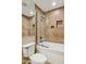 A bathroom featuring a shower with tan tile and built-in shelves, with a white toilet in the foreground at 13248 N 12Th Pl, Phoenix, AZ 85022