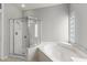 Bright bathroom showing a walk-in shower, soaking tub, and glass block window at 15704 W Sentinel Dr, Sun City West, AZ 85375