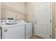 A functional laundry room with a washer, dryer, shelving and exterior door at 17061 W Peregrine Ln, Surprise, AZ 85387