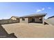 View of the unlandscaped backyard, block fence and covered patio at 17299 W Desert Sage Dr, Goodyear, AZ 85338