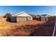 Backyard view shows the home's exterior, spacious gravel yard, simple landscaping and fencing around the property at 1937 W Burgess Ln, Phoenix, AZ 85041