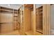 Spacious walk-in closet with wood-finished shelving, hanging rods, and glass-fronted cabinets at 24084 N 77Th St, Scottsdale, AZ 85255