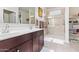 Bathroom featuring double vanity, tiled shower with glass door, and neutral decor at 24338 W Albeniz Pl, Buckeye, AZ 85326