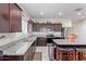 Well-lit kitchen features granite countertops, stainless steel appliances, and a central island with barstool seating at 24338 W Albeniz Pl, Buckeye, AZ 85326