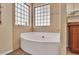 A luxurious soaking tub surrounded by natural light and tiled walls offers a serene bathroom experience at 311 W Georgia Ave, Phoenix, AZ 85013