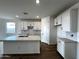 Bright kitchen features white cabinets, modern fixtures, an island with stainless steel sink and tile backsplash at 4328 E Bradford Ave, San Tan Valley, AZ 85140