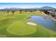 Aerial view of the golf course showcasing lush greenery, a serene pond, and picturesque mountain views at 4439 E Ficus Way, Gilbert, AZ 85298