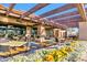 Outdoor patio with beautiful stone pillars, a pergola, and a garden with colorful yellow flowers at 4439 E Ficus Way, Gilbert, AZ 85298