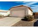 Beige single-story home with a 2-car garage, gravel landscaping and a concrete driveway beneath a bright blue sky at 8553 N 112Th Ave, Peoria, AZ 85345