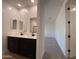 Double sink bathroom with modern fixtures and cabinetry, leading to carpeted bedroom at 9526 W Luxton Ln, Tolleson, AZ 85353