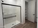 Modern bathroom featuring a glass shower, white walls, and wood-look tile flooring at 9526 W Luxton Ln, Tolleson, AZ 85353