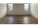 Neutral bedroom with wood-look tile flooring and two windows, offering a serene retreat at 9526 W Luxton Ln, Tolleson, AZ 85353