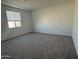 Spacious bedroom featuring plush carpet flooring and natural light from a window at 9526 W Luxton Ln, Tolleson, AZ 85353