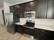 Kitchen featuring stainless steel appliances and a range with dark cabinetry and bright countertops at 9526 W Luxton Ln, Tolleson, AZ 85353