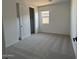 Well-lit bedroom with neutral carpet, a window, and a closet with a white door at 9534 W Luxton Ln, Tolleson, AZ 85353