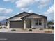 One-story home with gray siding, dark gray garage door, and landscaping at 9534 W Luxton Ln, Tolleson, AZ 85353