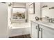 Bright bathroom features a soaking tub with a window overlooking the fenced backyard and a vanity with white cabinets at 10971 W Tonopah Dr, Peoria, AZ 85373
