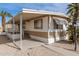 Tan mobile home with carport, steps, and palm trees at 11411 N 91 Ave # 56, Peoria, AZ 85345