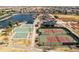 Aerial view of community sports facilities with tennis courts, basketball courts, playground, lake, and community homes at 18716 N Jameson Dr, Maricopa, AZ 85138