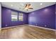 A bedroom featuring hardwood floors, painted purple walls, and a window allowing natural light at 18716 N Jameson Dr, Maricopa, AZ 85138
