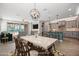 A staged dining room shows the dining table and chairs, a modern chandelier, and open access to the kitchen at 18716 N Jameson Dr, Maricopa, AZ 85138
