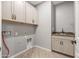Bright laundry room features tile floors, overhead cabinets, and a utility sink at 18716 N Jameson Dr, Maricopa, AZ 85138