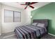 Bedroom with wood-look floors, ceiling fan, and green accent wall at 18907 N Vemto St, Maricopa, AZ 85138