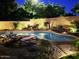 Backyard pool with lounge chairs on brick patio surrounded by lush green trees and landscape lighting at 2073 E Wildhorse Dr, Chandler, AZ 85286