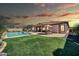 Spacious backyard with a pool, covered patio, dining area, and lush green lawn at sunset at 30696 N 130Th Ln, Peoria, AZ 85383