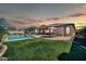 Spacious backyard with a pool, covered patio, dining area, and lush green lawn at sunset at 30696 N 130Th Ln, Peoria, AZ 85383