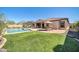 Lush backyard with a sparkling pool, artificial turf, covered patio, and outdoor kitchen area at 30696 N 130Th Ln, Peoria, AZ 85383