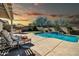 Outdoor living space with a pool, lounging area, outdoor kitchen, and lush desert landscaping at 30696 N 130Th Ln, Peoria, AZ 85383