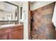 Updated bathroom featuring a large shower with earth-toned tiles and a framed mirror above a wood vanity at 30696 N 130Th Ln, Peoria, AZ 85383